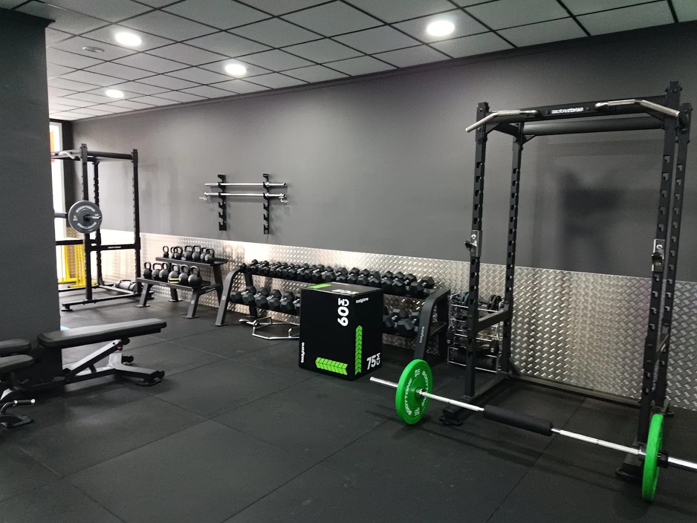 Zona de fuerza con racks, bancos, mancuernas, kettlebells y cajones